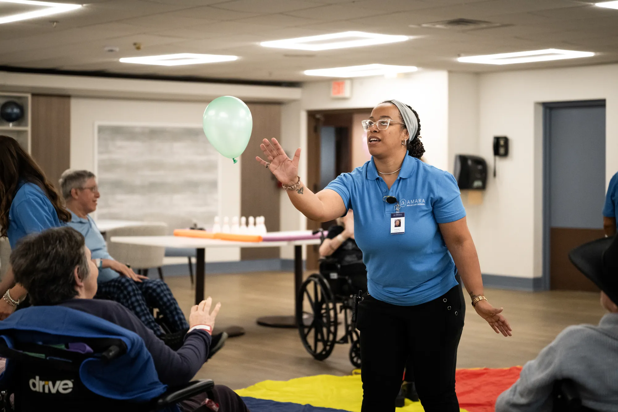 An Amara activities staff member leading a balloon game with residents seated in a circle