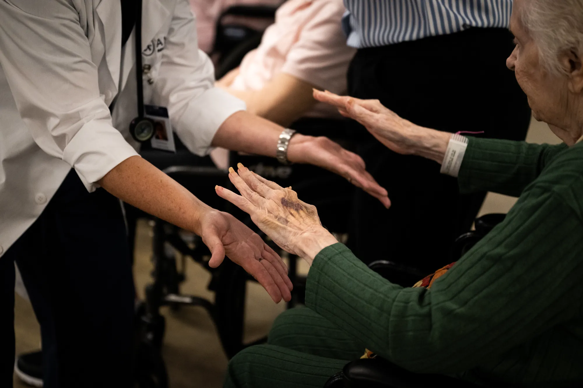 Residents reaching out to hold a staff member's hands during an Amara activity session
