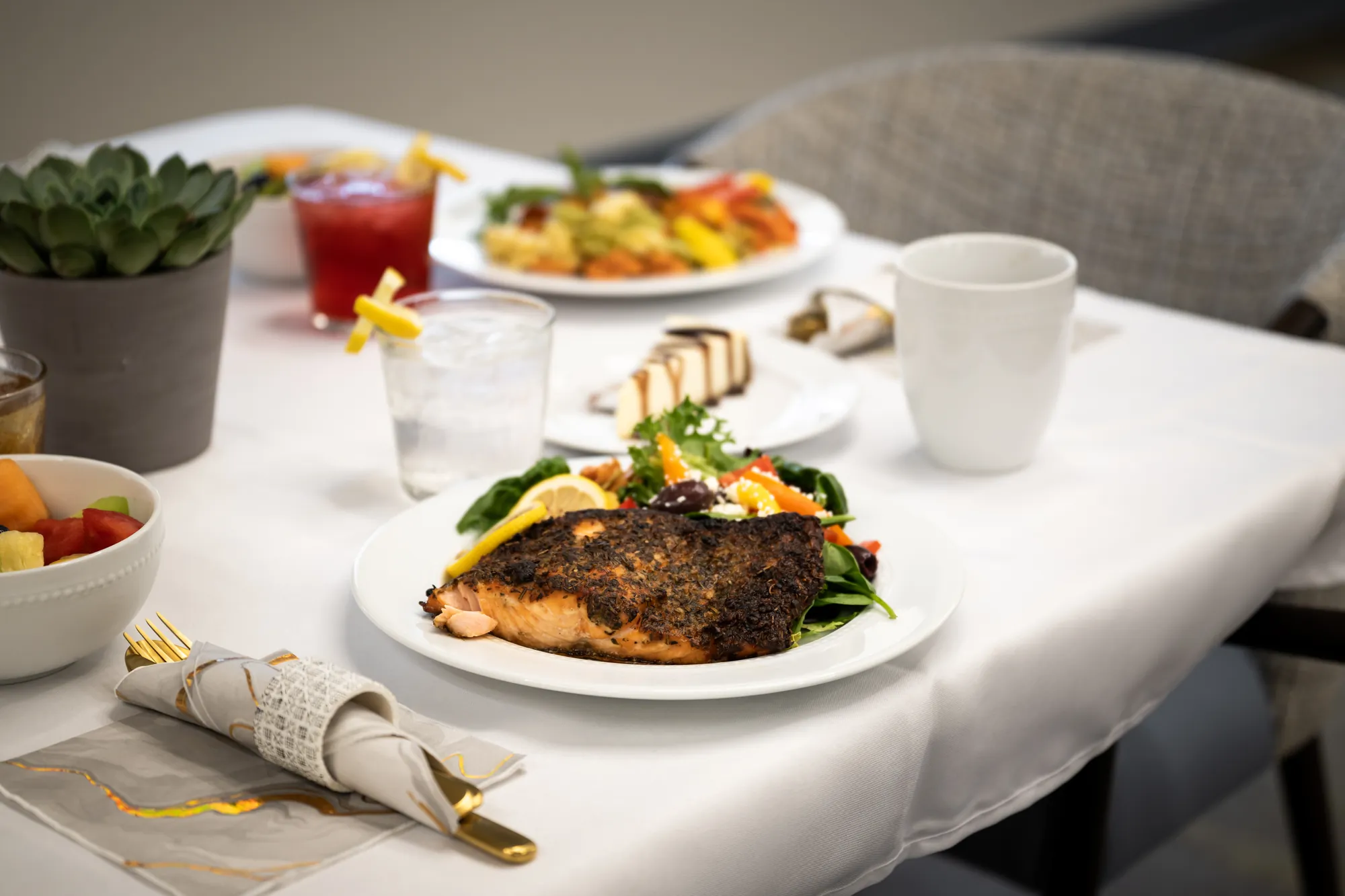 A plated fish entrée and a drink on a linen-set table in the Amara dining room
