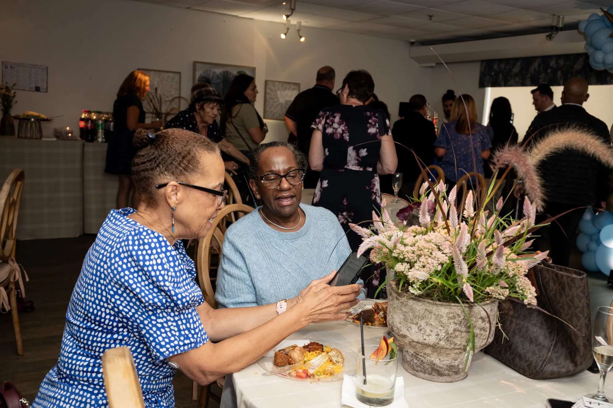 Guests talking beside a floral arrangement at the Amara open house