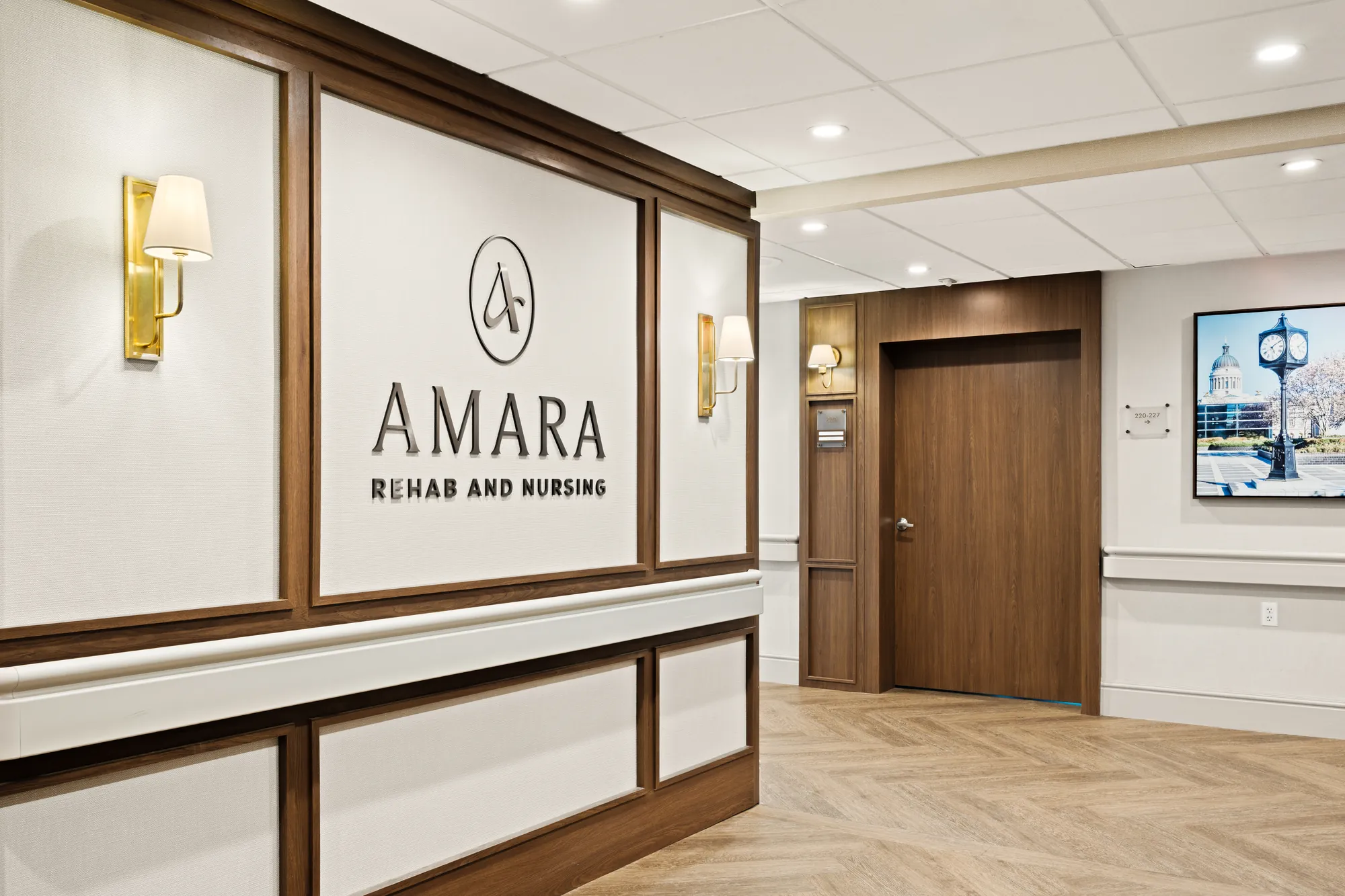 The AMARA Rehab and Nursing wordmark on the wood-panelled lobby wall beside a wall sconce