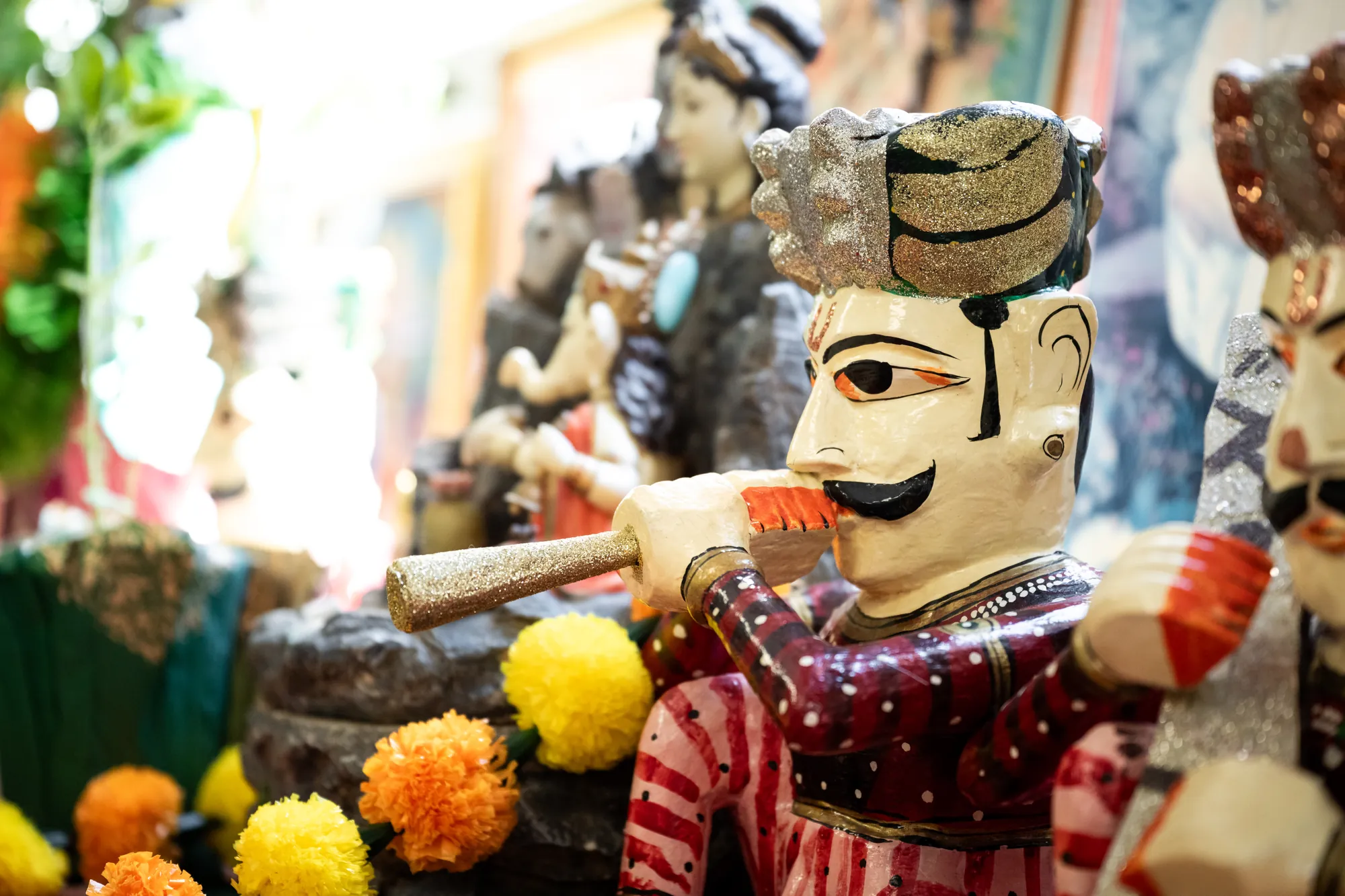 Painted devotional figures and marigolds in close detail at the Amara shrine