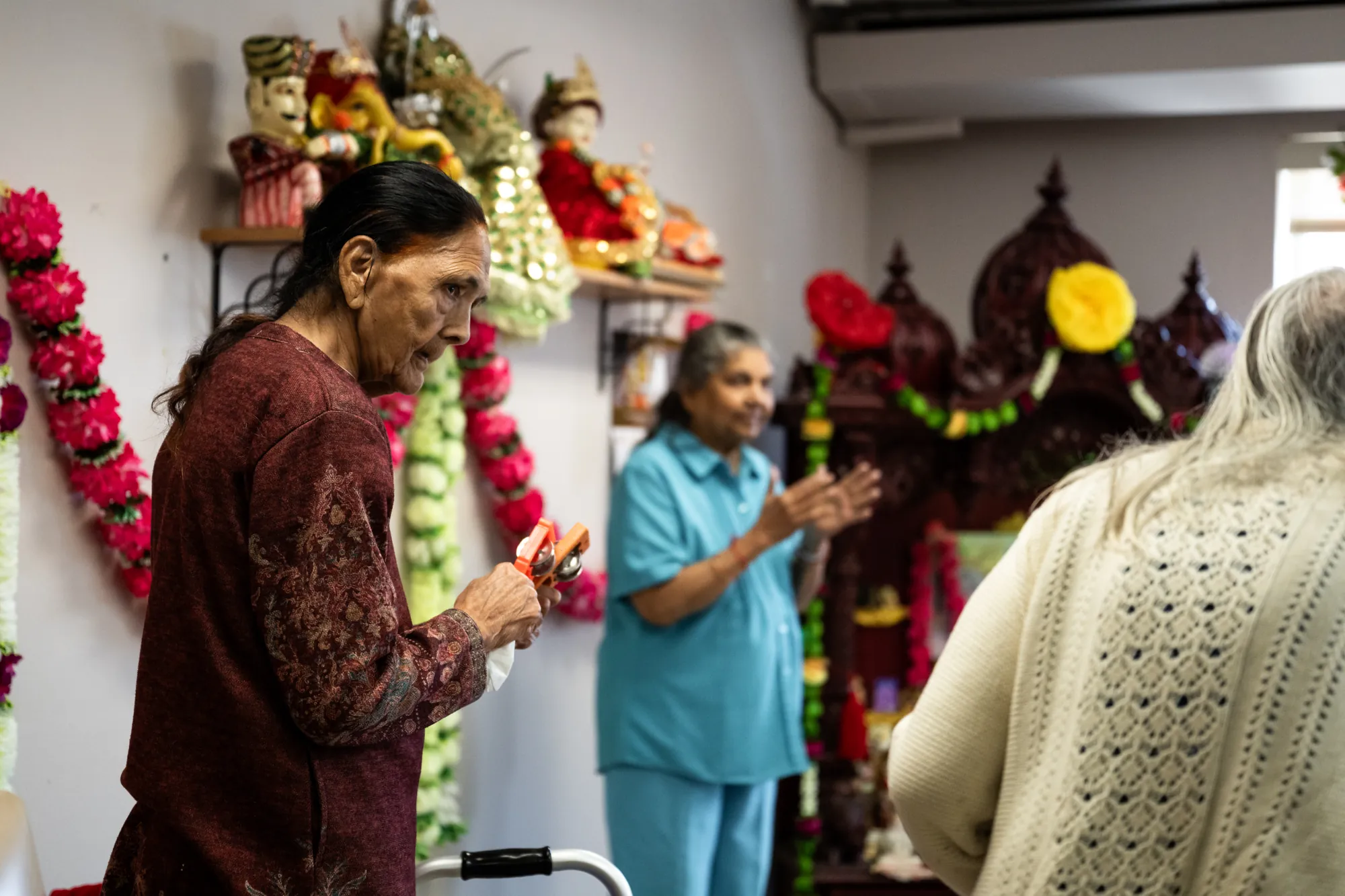 Residents at Amara standing in prayer before the shrine, garlands overhead