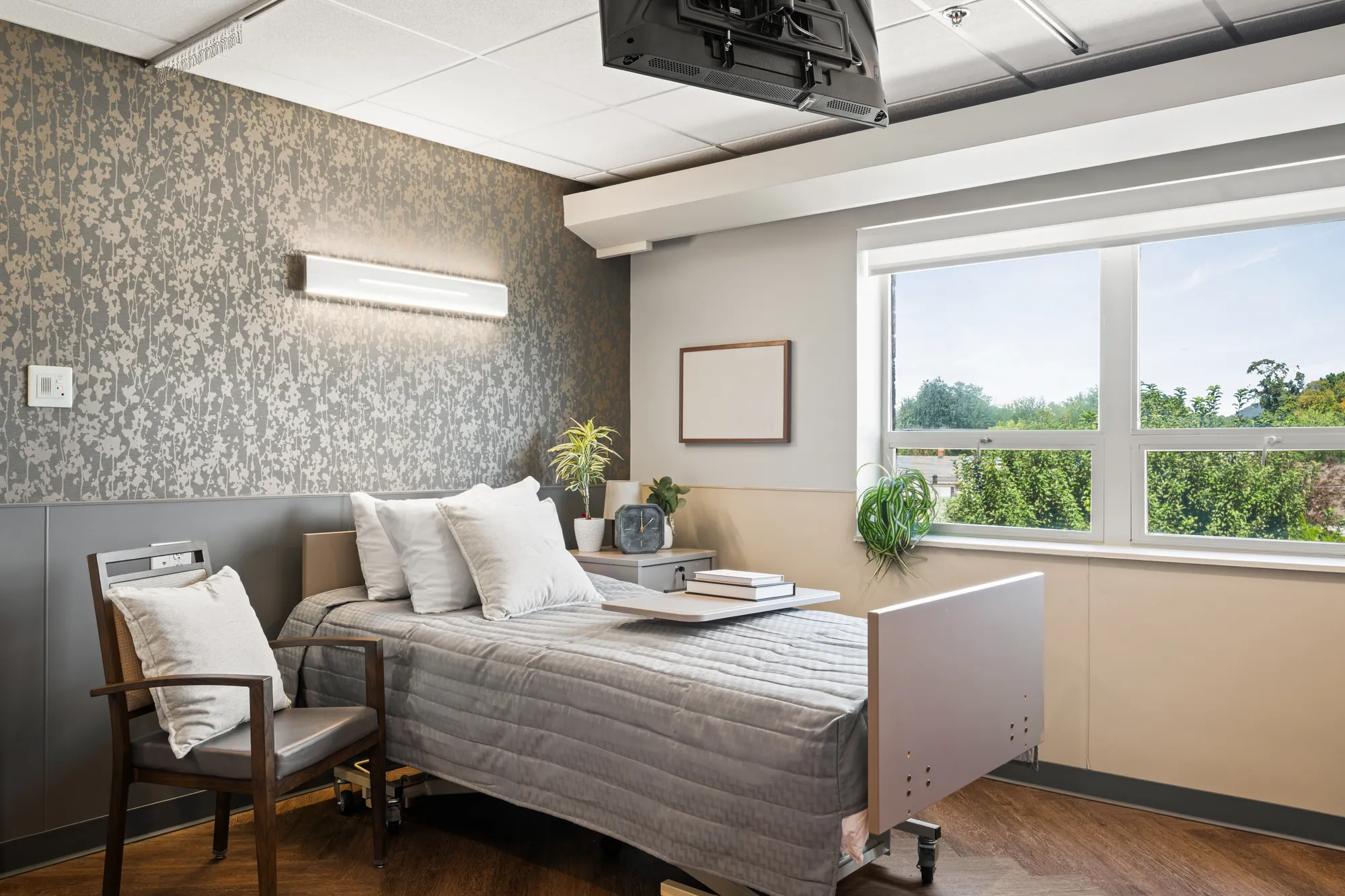 An Amara resident room with a made bed, armchair and a window onto the treeline