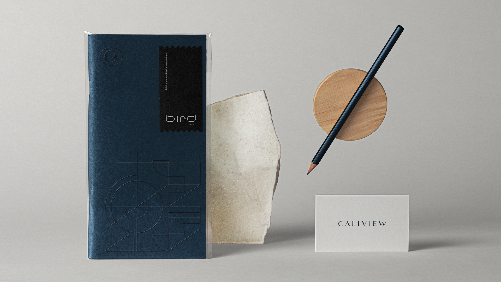 Caliview Estates navy brochure in a sleeve beside a stone fragment, a wooden disc, and a business card