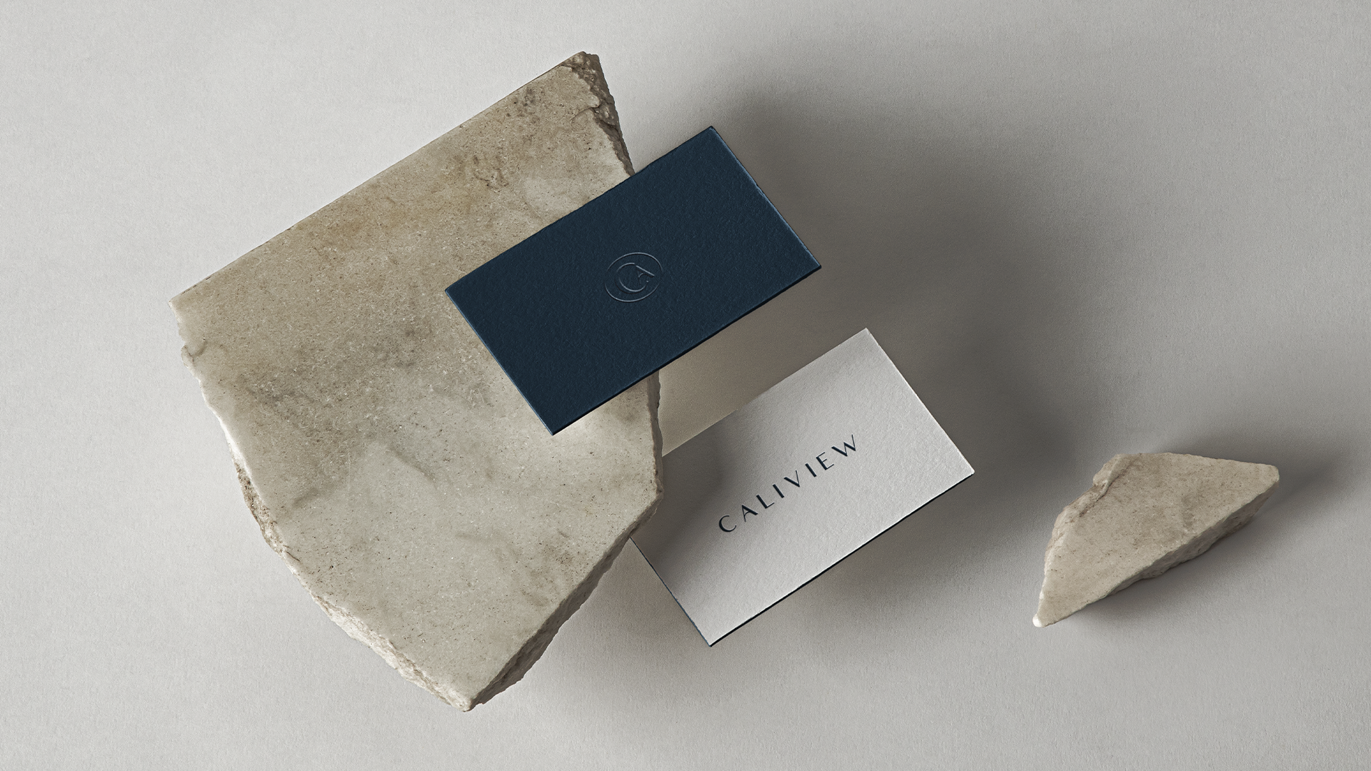 Navy and white Caliview Estates business cards resting on rough stone
