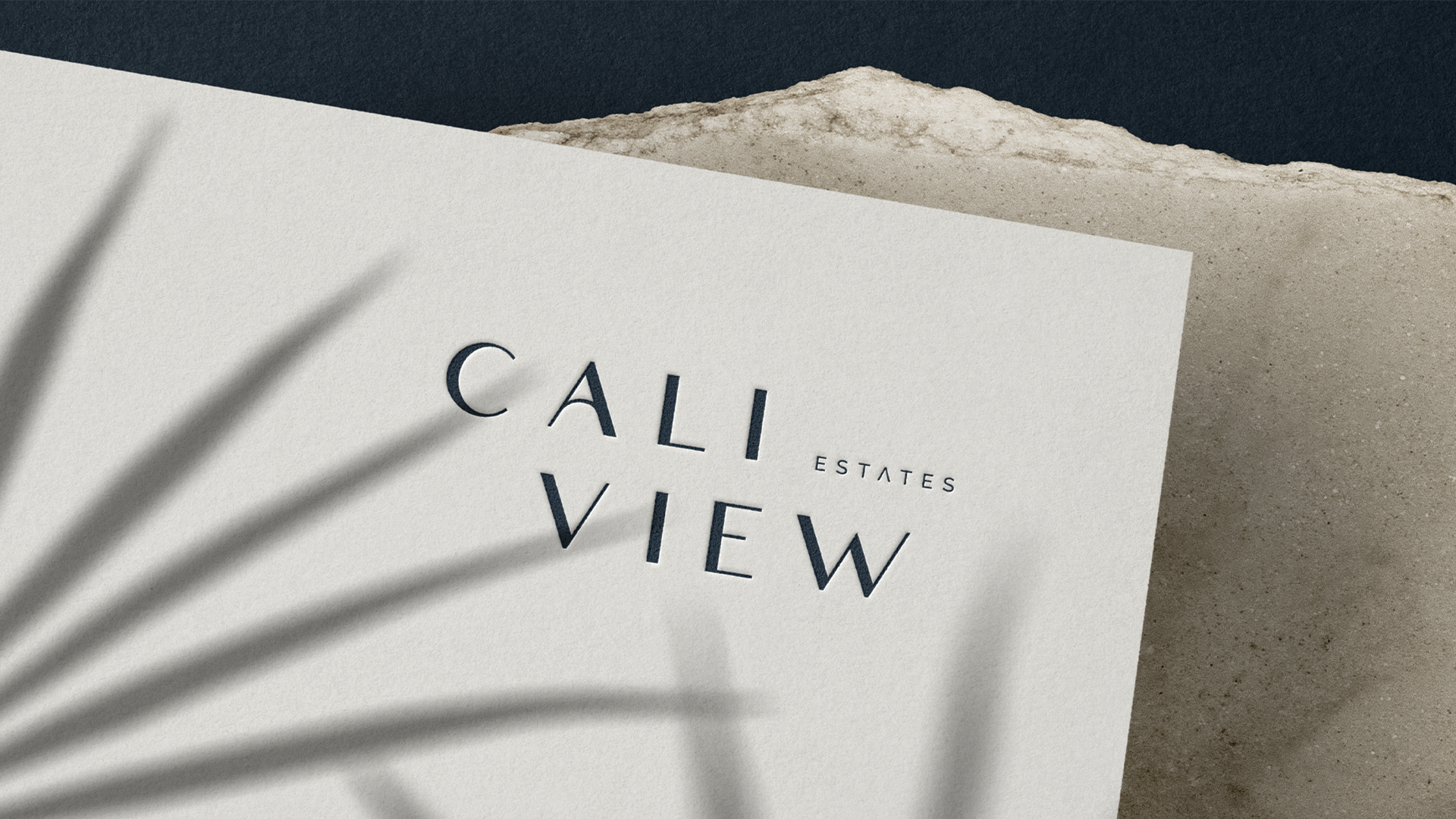 Caliview Estates stacked wordmark debossed on cream card, with palm shadows across it