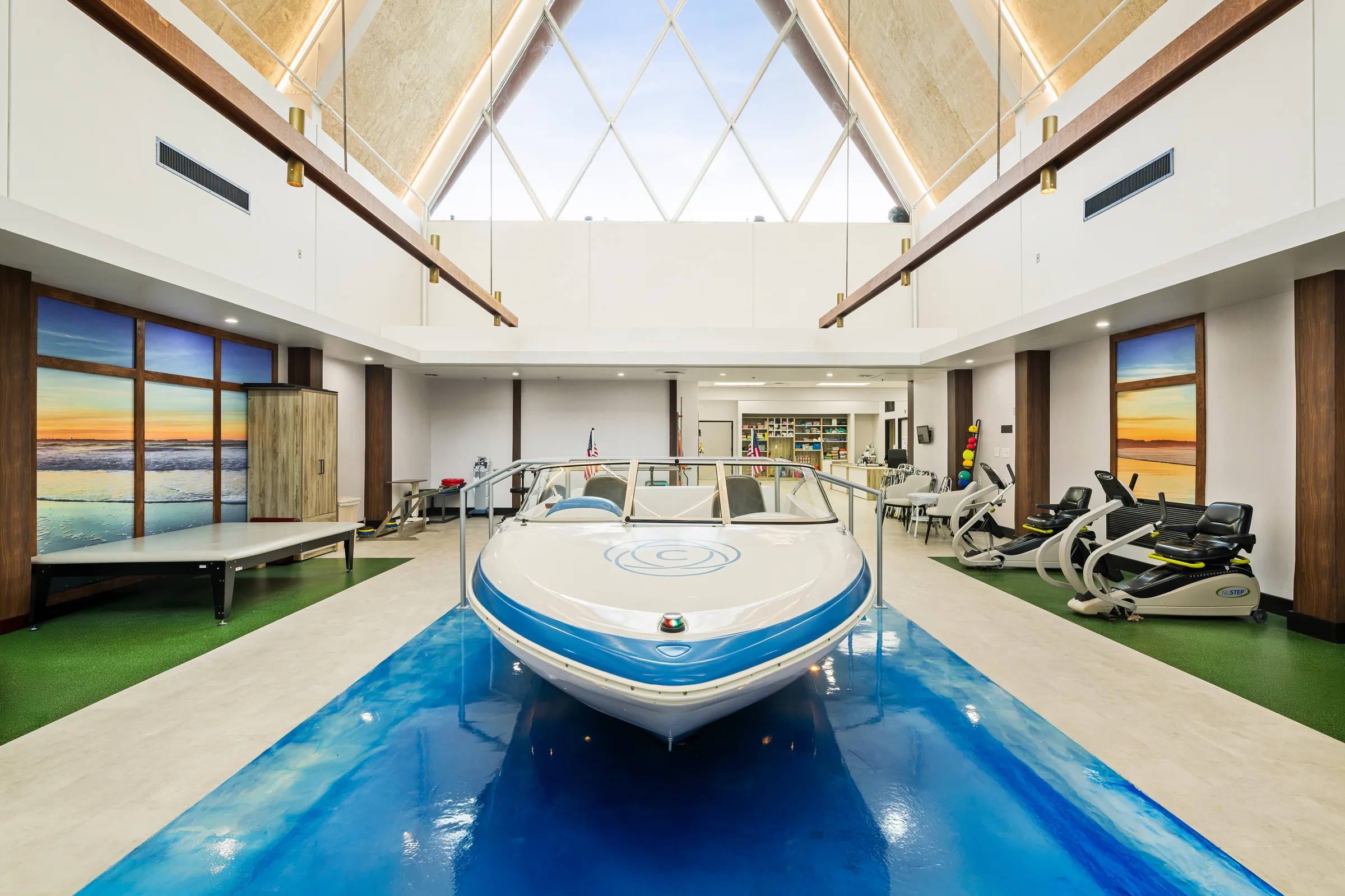 Carlton Shores rehab gym with a real boat installed under a diamond skylight, beach murals on either side