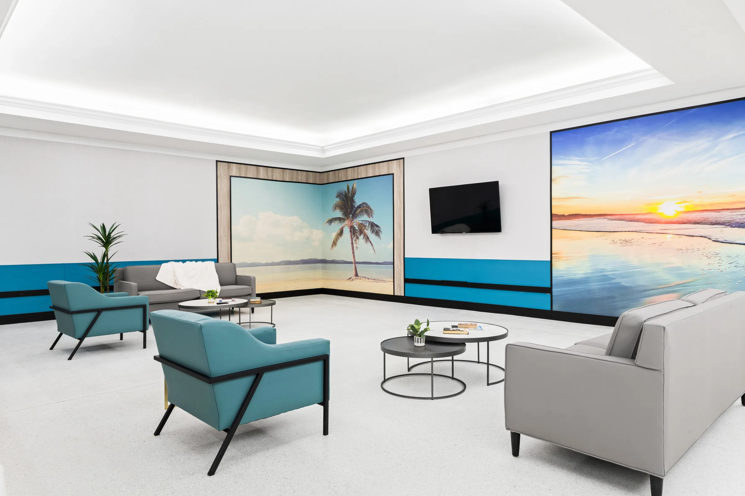 Carlton Shores resident lounge with palm tree mural, sunset wall art, and teal accent furniture