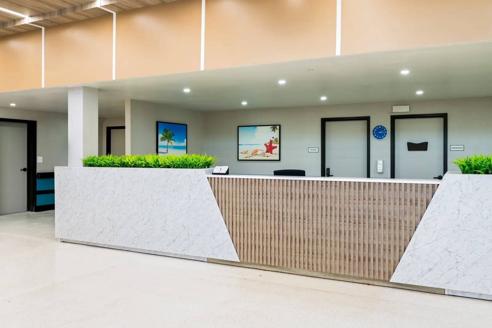 Carlton Shores reception desk with marble base, wood slat front, and live planter
