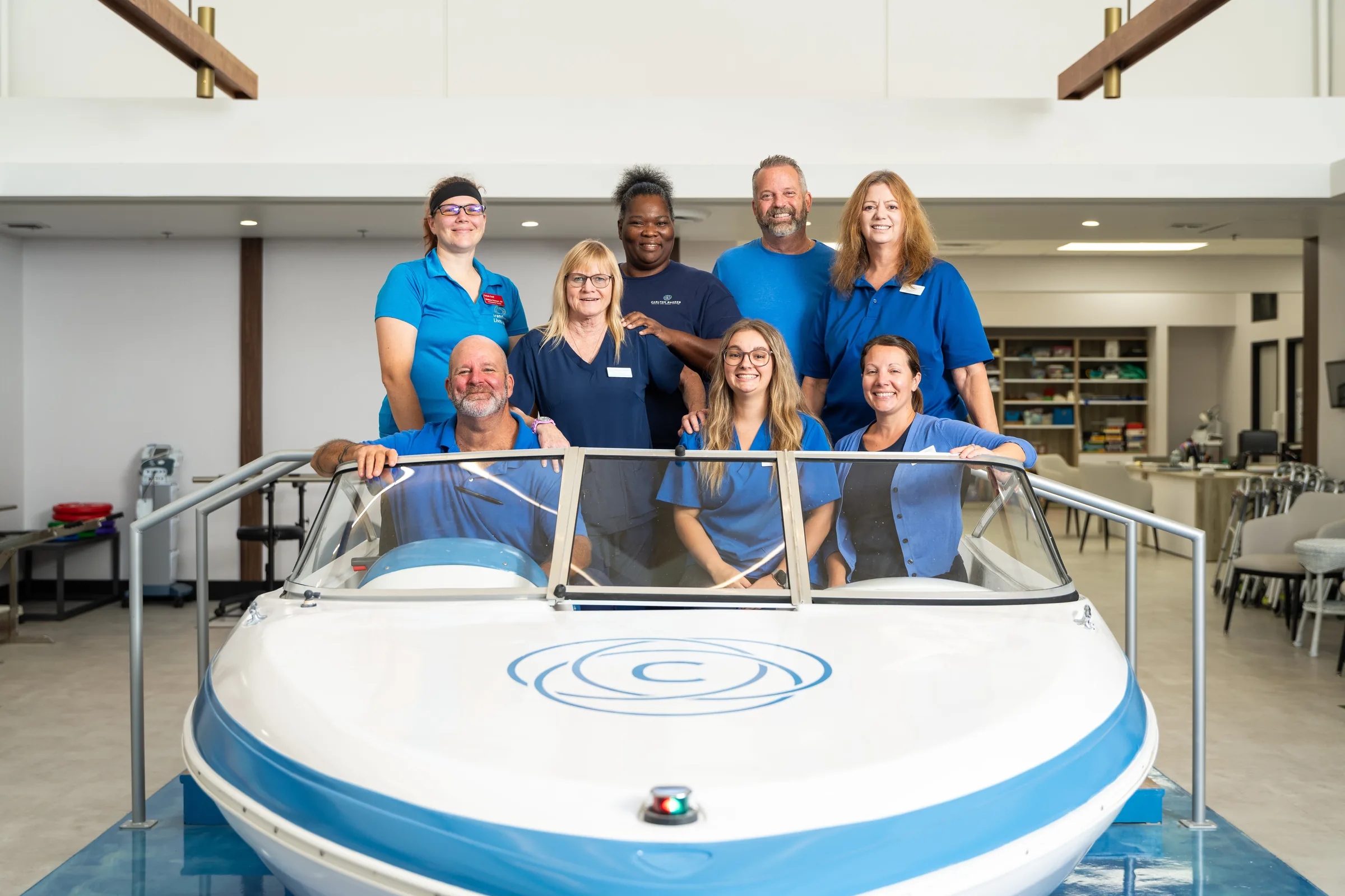 Carlton Shores staff group portrait around the boat in the rehab gym