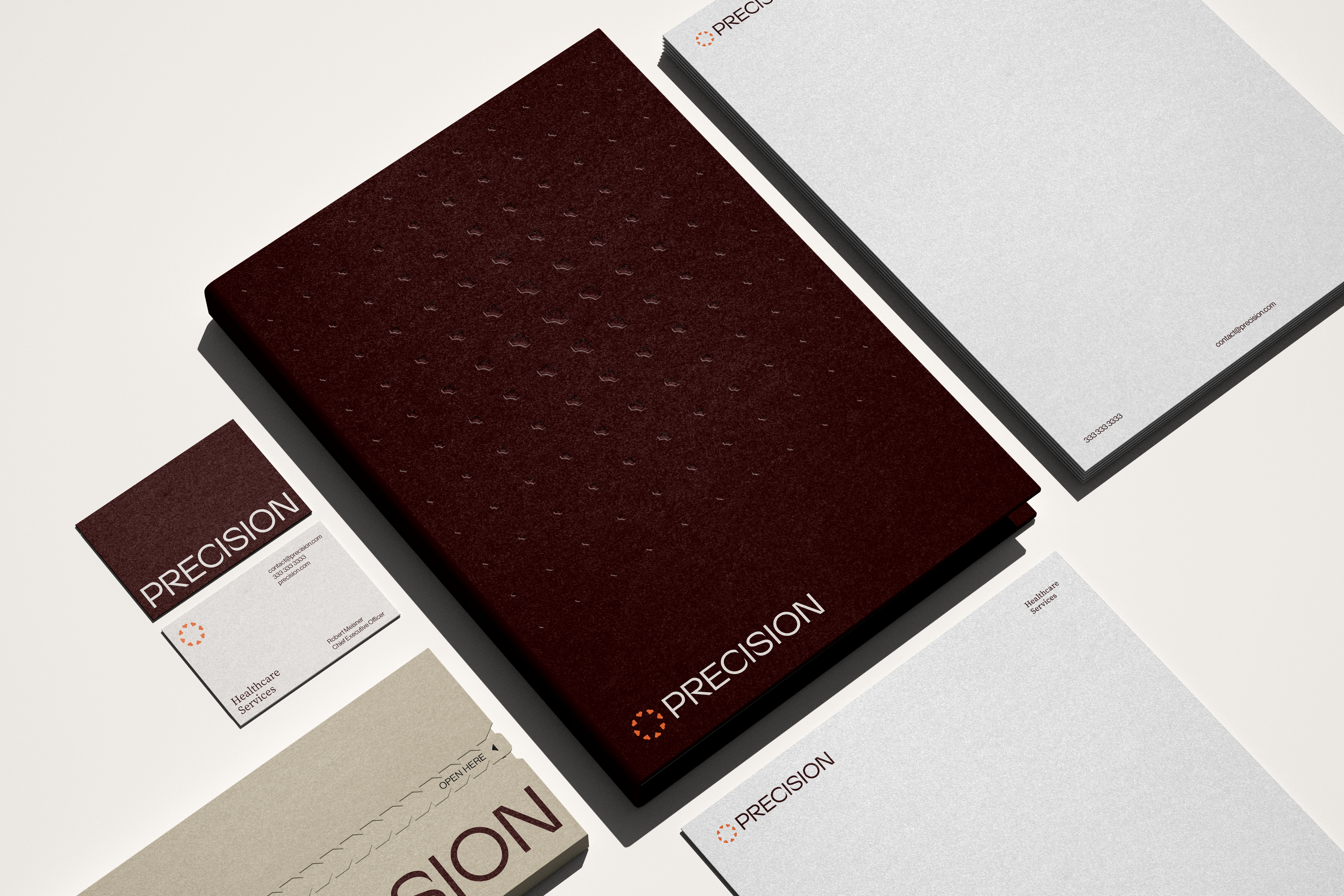 Precision stationery flat lay with an oxblood embossed folder, letterhead, business cards, and envelope