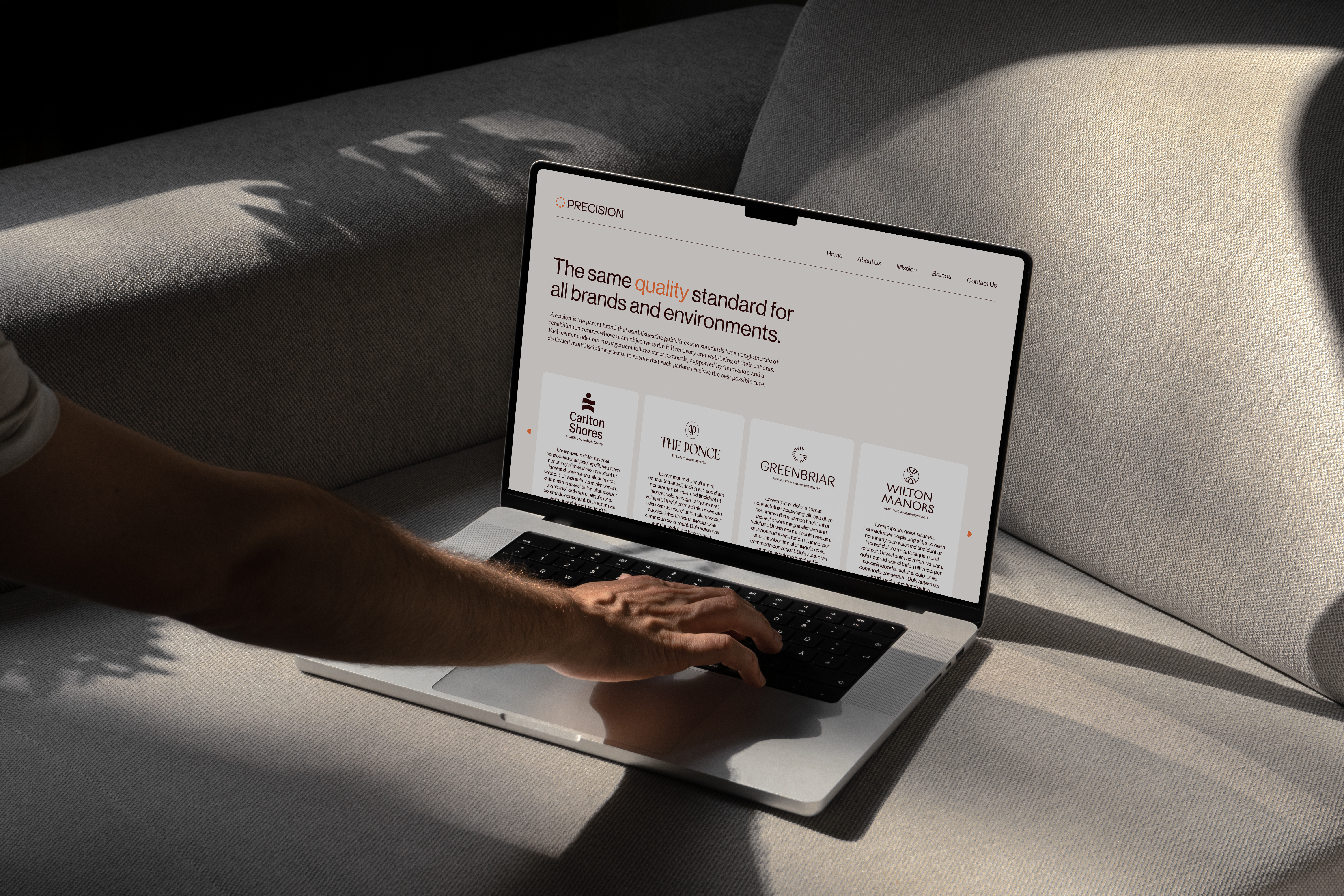 Laptop on a sofa showing the Precision site section on one quality standard across all brands