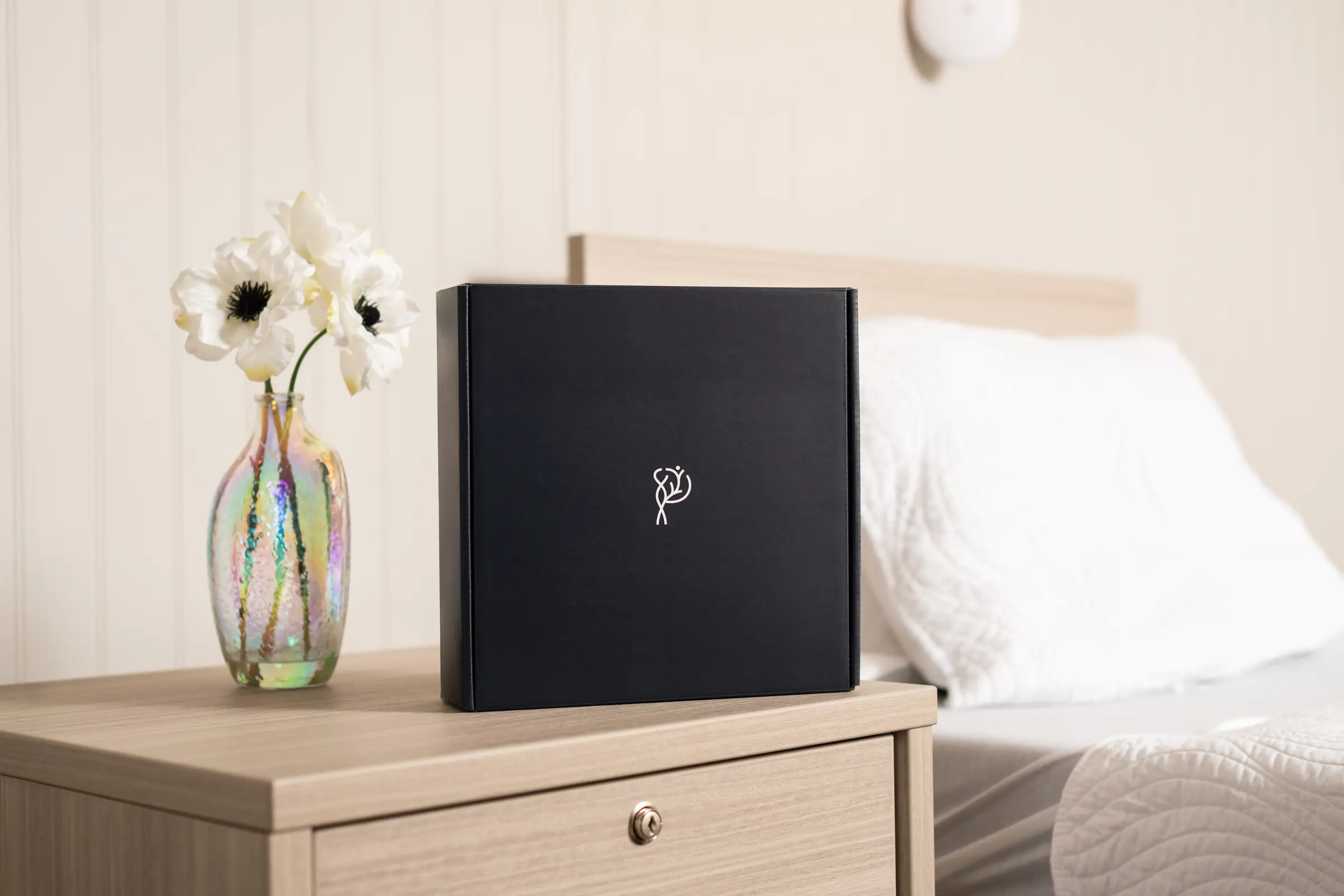 Branded welcome box and flowers arranged on a bedside table