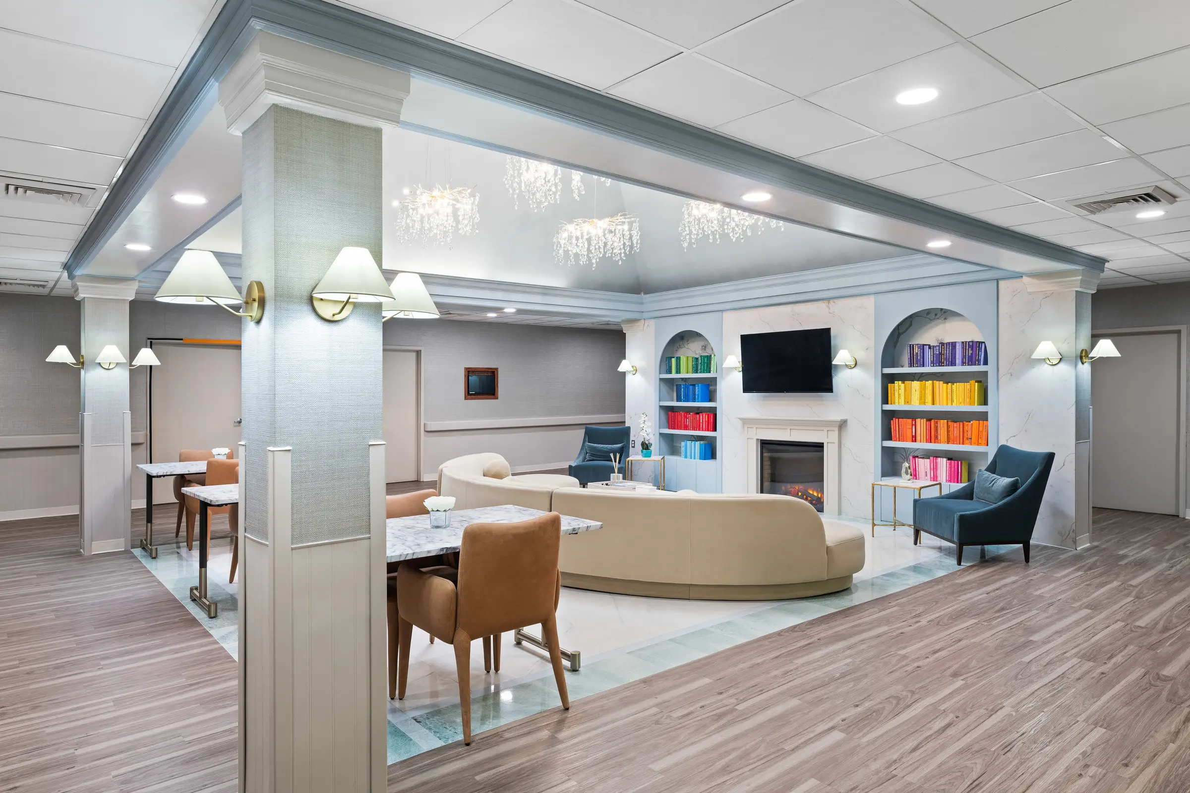 Lounge with color-arranged bookshelves, lit fireplace, and fresh seating