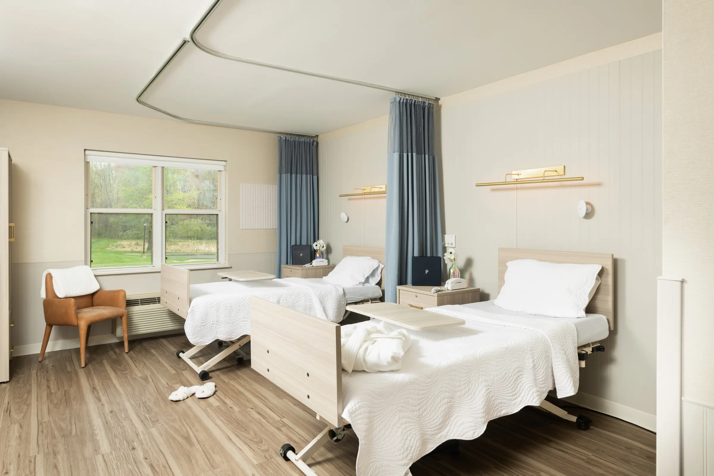Resident room with crisp white bedding, robe, and slippers set out