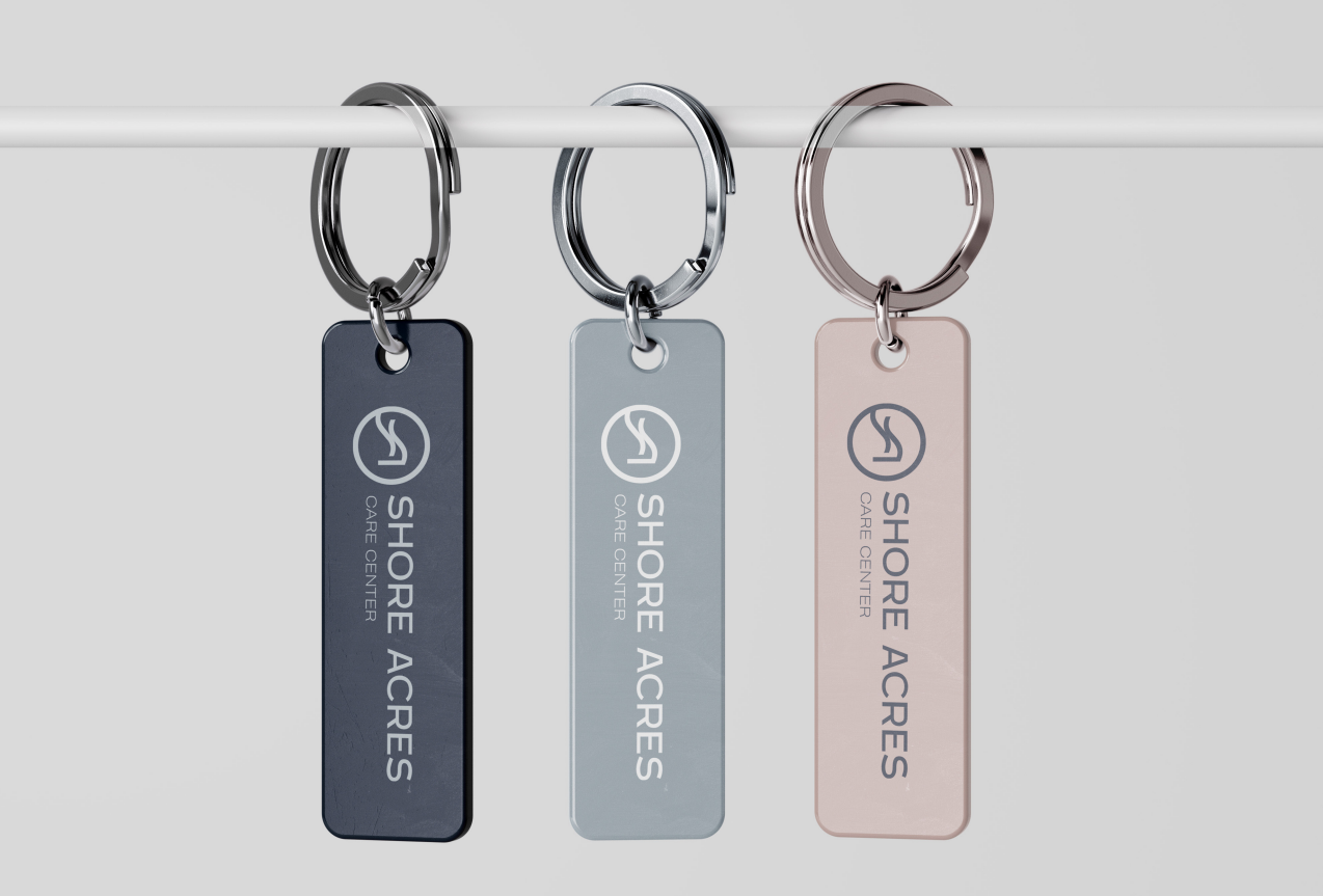 Three Shore Acres Care Center keyrings in navy, grey, and blush