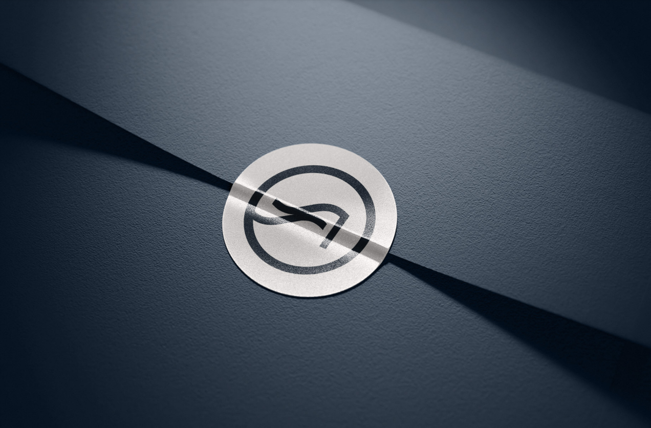 Circular Shore Acres monogram sticker on a navy surface, cut by a shaft of light