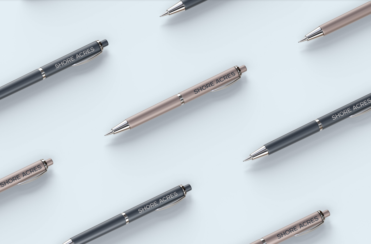 Shore Acres branded pens in navy and blush, arranged in a repeating diagonal pattern