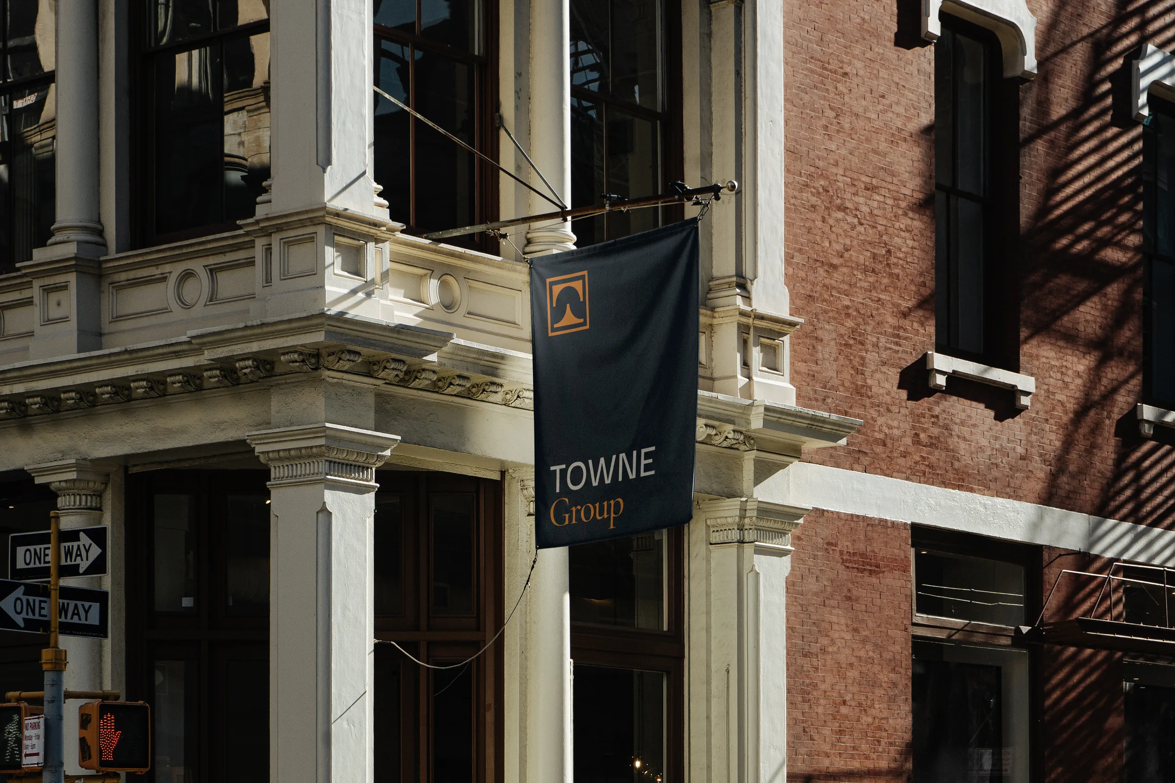 Navy Towne Group banner flag mounted on a historic building corner, with the orange square logo mark